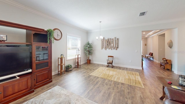 living area featuring visible vents, crown molding, baseboards, an inviting chandelier, and wood finished floors