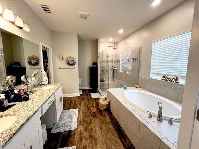 bathroom featuring visible vents, a stall shower, wood finished floors, a bath, and a sink