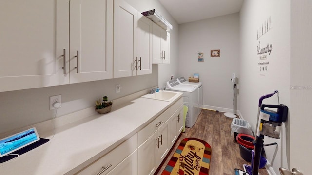 washroom with washer and clothes dryer, a sink, dark wood finished floors, cabinet space, and baseboards