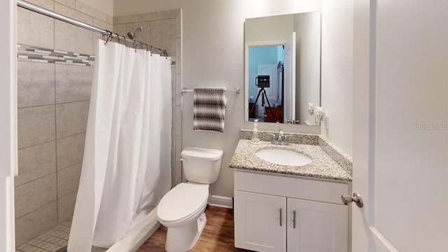 full bath with a tile shower, toilet, vanity, and wood finished floors