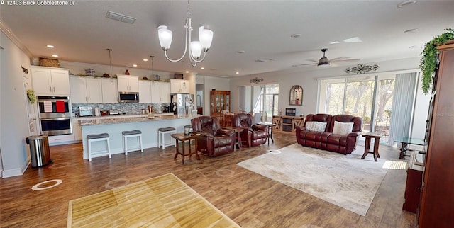 living area with visible vents, crown molding, and wood finished floors