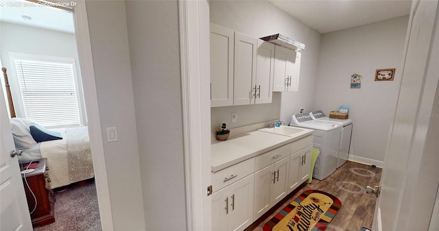 clothes washing area featuring washing machine and clothes dryer, cabinet space, baseboards, and a sink