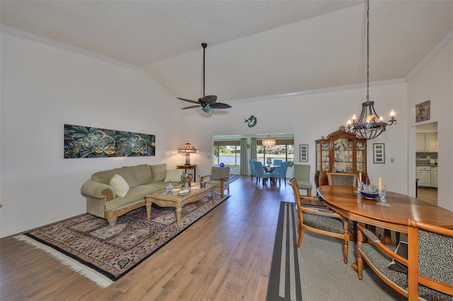 living area featuring ceiling fan with notable chandelier, high vaulted ceiling, ornamental molding, and wood finished floors