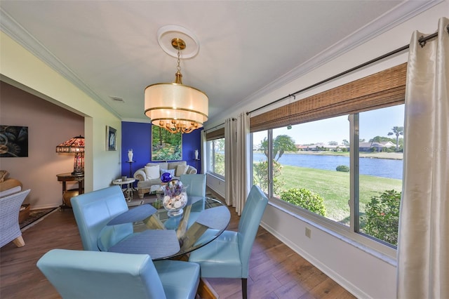 dining area with a water view, wood finished floors, crown molding, baseboards, and a chandelier