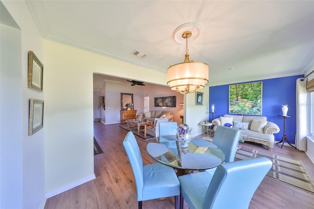 dining space with crown molding, wood finished floors, visible vents, and baseboards