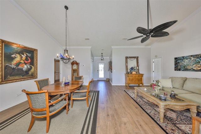 dining room with crown molding, baseboards, vaulted ceiling, ceiling fan with notable chandelier, and wood finished floors