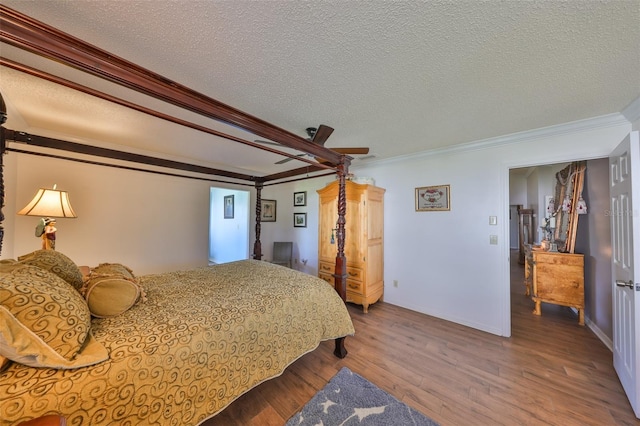 bedroom with a ceiling fan, a textured ceiling, wood finished floors, crown molding, and baseboards