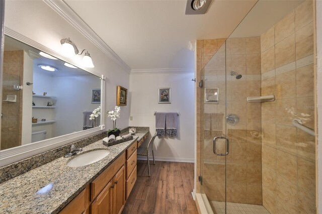 bathroom with a shower stall, crown molding, baseboards, wood finished floors, and vanity