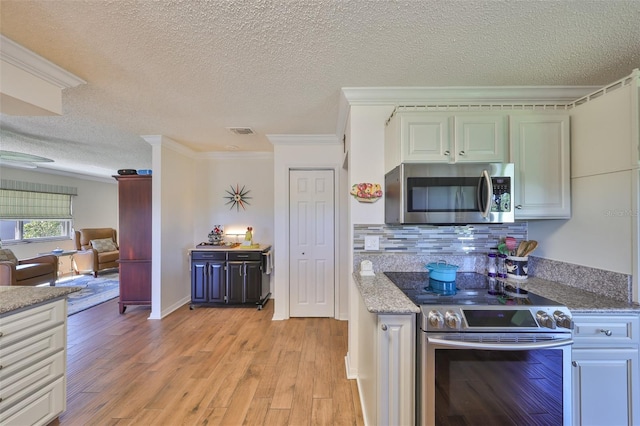 kitchen with visible vents, ornamental molding, light wood-style floors, appliances with stainless steel finishes, and decorative backsplash