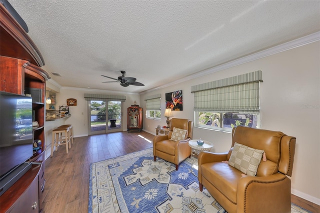 living area featuring hardwood / wood-style floors, a ceiling fan, baseboards, ornamental molding, and a textured ceiling