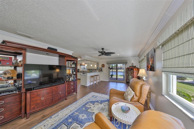 living room featuring visible vents, a textured ceiling, wood finished floors, crown molding, and ceiling fan