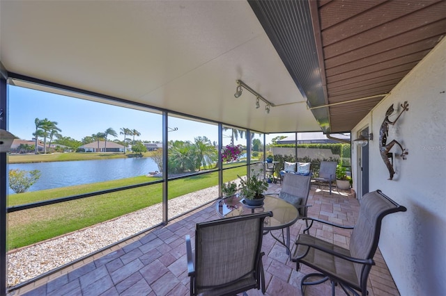 sunroom / solarium with a water view and track lighting