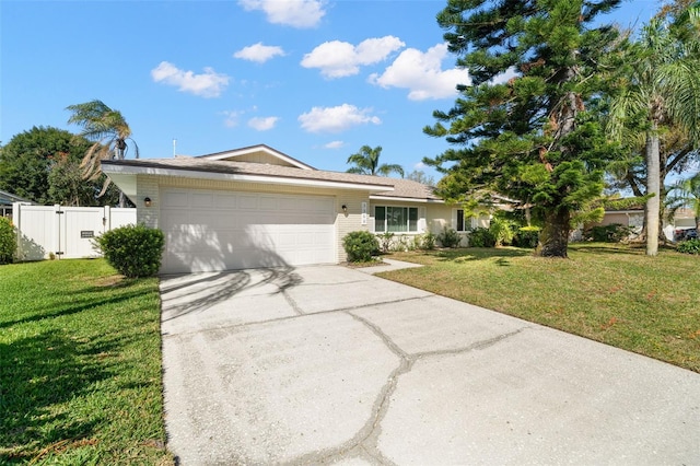 ranch-style house featuring a front lawn, fence, driveway, an attached garage, and a gate