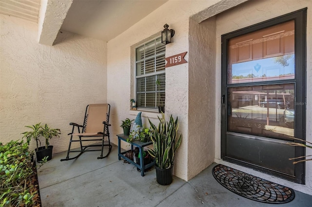 entrance to property with stucco siding and covered porch