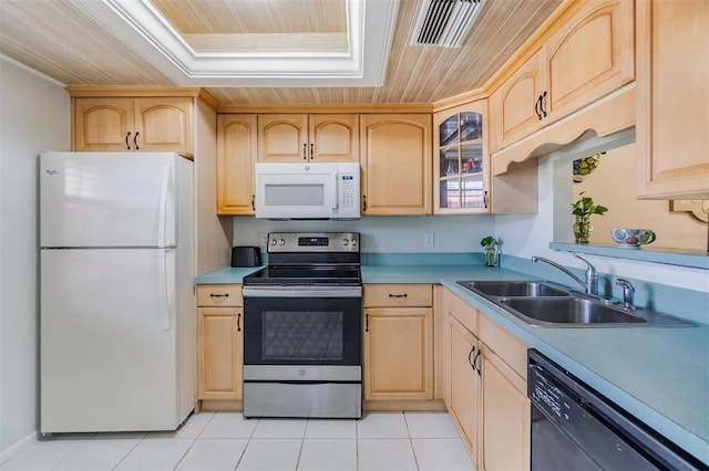 kitchen with a sink, white appliances, and light brown cabinetry