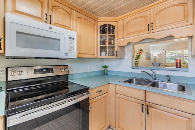 kitchen featuring white microwave, light brown cabinetry, light countertops, electric stove, and glass insert cabinets