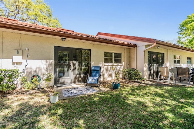 rear view of house with a tiled roof, stucco siding, and a patio area