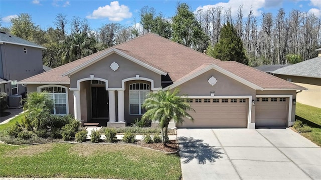 view of front facade featuring a garage, a front yard, driveway, and stucco siding