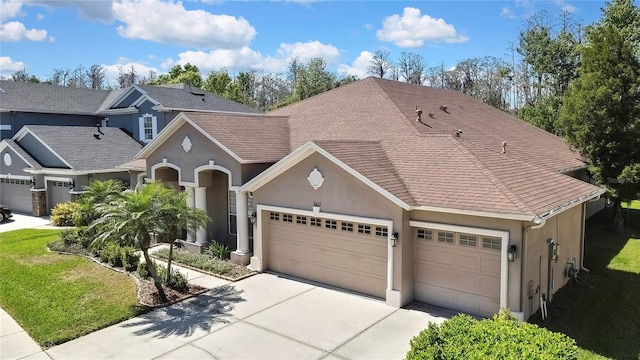 view of front facade featuring a front lawn, concrete driveway, roof with shingles, stucco siding, and a garage