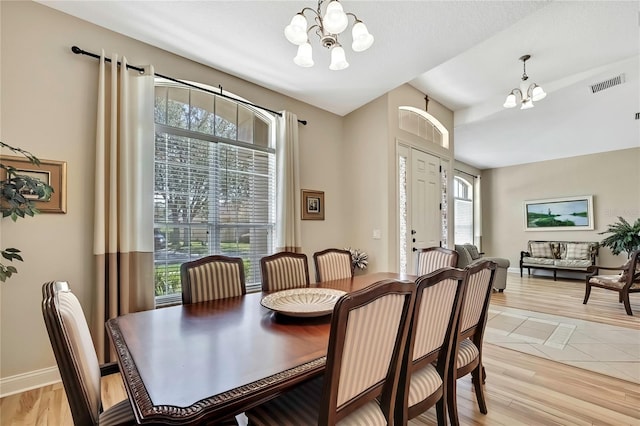 dining area featuring visible vents, a notable chandelier, a healthy amount of sunlight, and light wood-style flooring