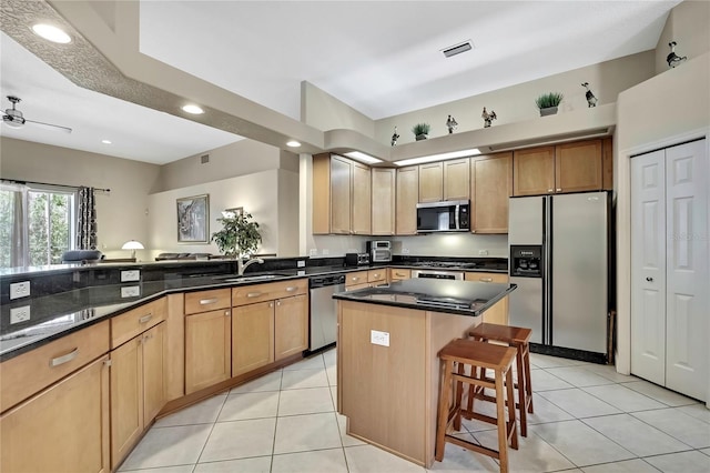 kitchen featuring light tile patterned flooring, a breakfast bar area, stainless steel appliances, and a sink