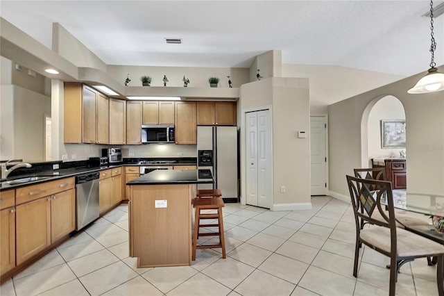 kitchen featuring a kitchen island, a sink, stainless steel appliances, a kitchen bar, and dark countertops