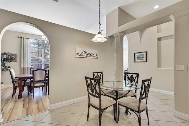 dining space featuring light tile patterned floors, decorative columns, baseboards, and vaulted ceiling