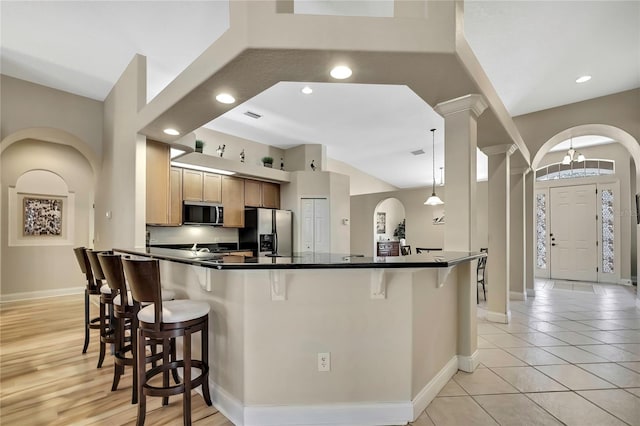 kitchen with a breakfast bar, dark countertops, a peninsula, and stainless steel appliances