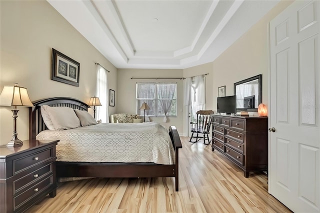 bedroom with a raised ceiling and light wood finished floors