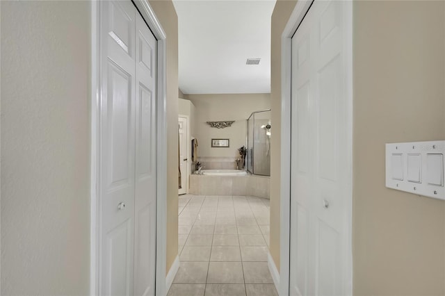 hall featuring light tile patterned floors and visible vents