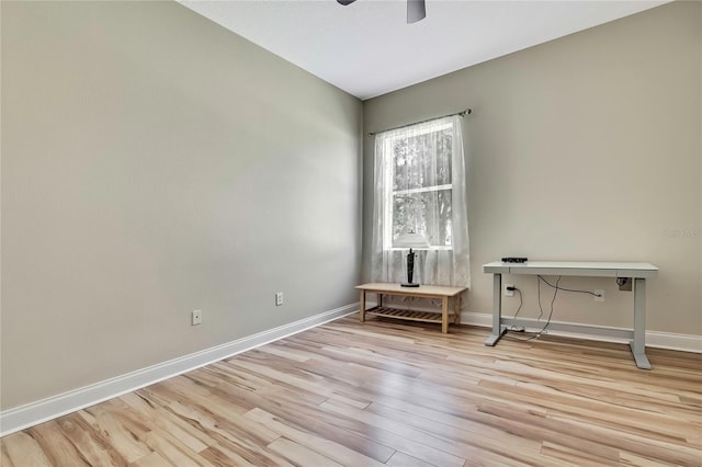 spare room featuring light wood-style flooring, a ceiling fan, and baseboards