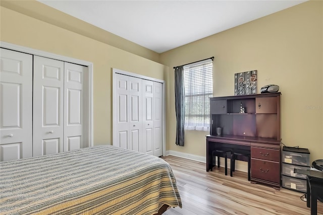 bedroom featuring two closets, light wood-type flooring, and baseboards