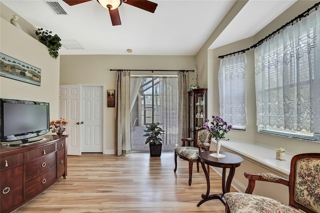 sitting room with visible vents, light wood-style flooring, baseboards, and ceiling fan