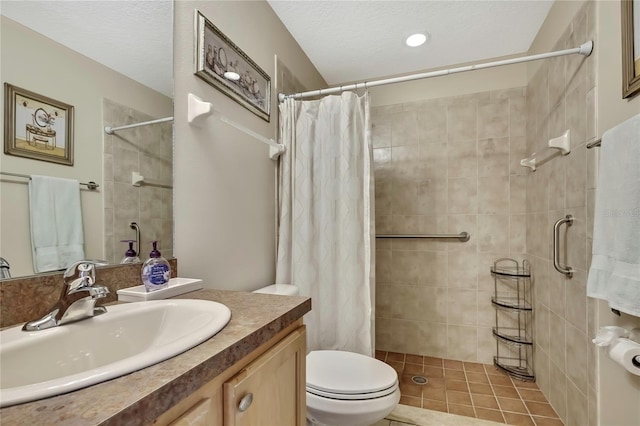 bathroom with tiled shower, toilet, vanity, and a textured ceiling