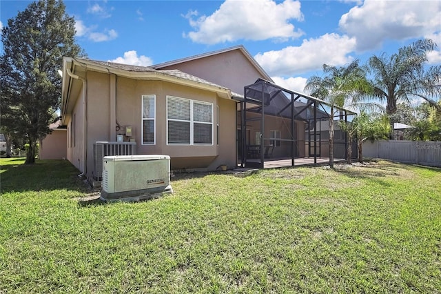 rear view of house with stucco siding, a yard, a lanai, and fence