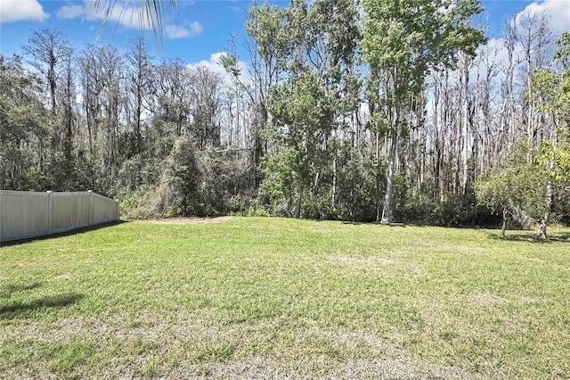 view of yard featuring fence and a wooded view