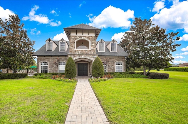 view of front facade with stone siding, a shingled roof, a front yard, and fence