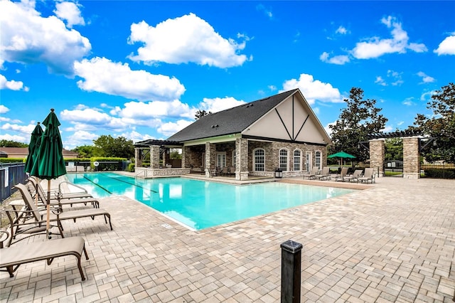 community pool with a patio, fence, an exterior structure, a pergola, and an outdoor structure