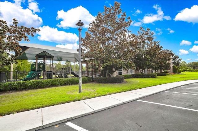 exterior space with a lawn, playground community, and uncovered parking