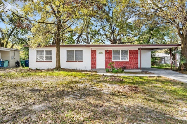 single story home featuring brick siding, an attached carport, and driveway