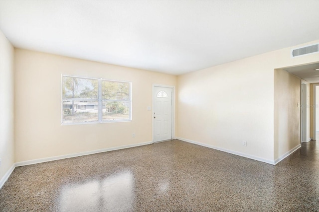 empty room with visible vents, speckled floor, and baseboards