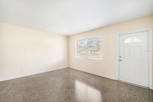 entrance foyer with speckled floor and baseboards