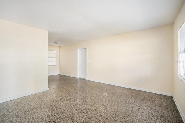 empty room with speckled floor and baseboards