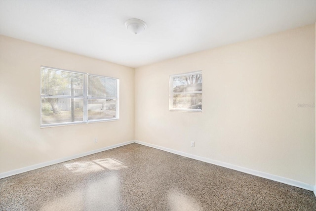 empty room with baseboards and speckled floor