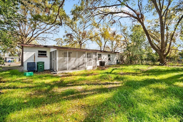 back of property with central air condition unit, a lawn, and a sunroom