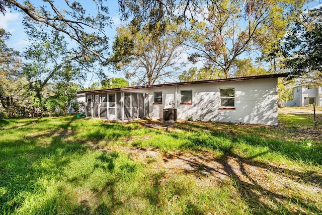 rear view of property with a lawn and a sunroom