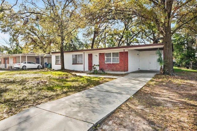 ranch-style house featuring a carport, concrete driveway, and brick siding