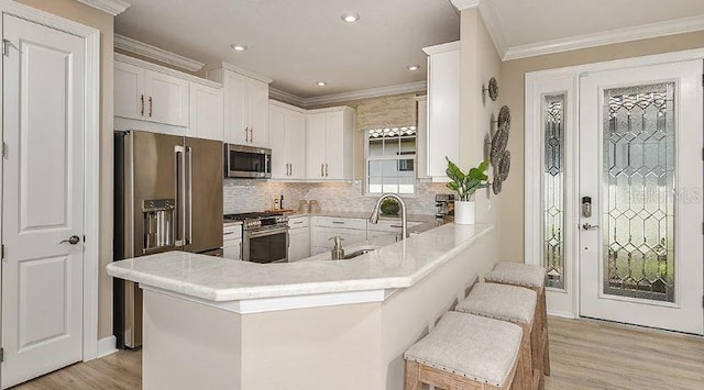 kitchen with light wood-style flooring, white cabinets, stainless steel appliances, and crown molding