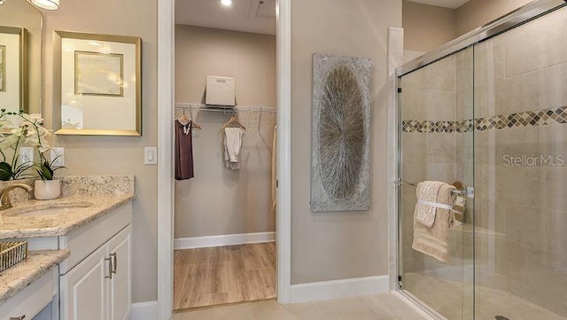 bathroom with baseboards, vanity, and a shower stall