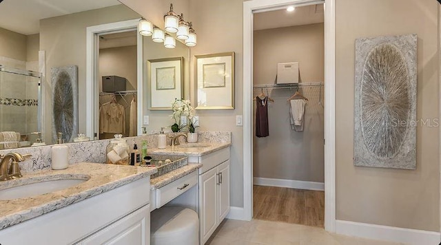 bathroom with vanity, a shower stall, a spacious closet, and baseboards